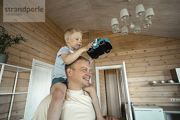 Vater trägt verspielten Sohn zu Hause auf den Schultern