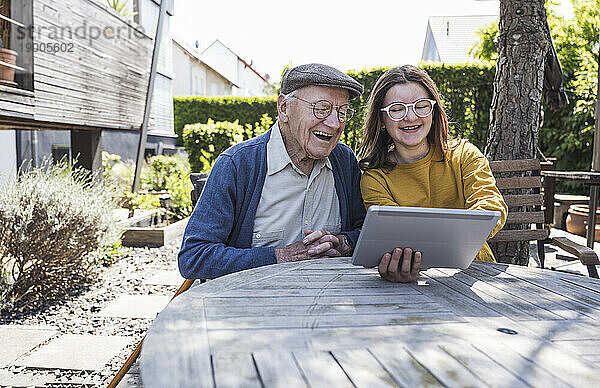 Glückliches Mädchen bringt Großvater im Hinterhof Tablet-PC bei