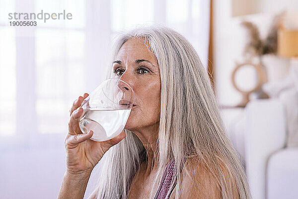 Reife Frau trinkt zu Hause Wasser