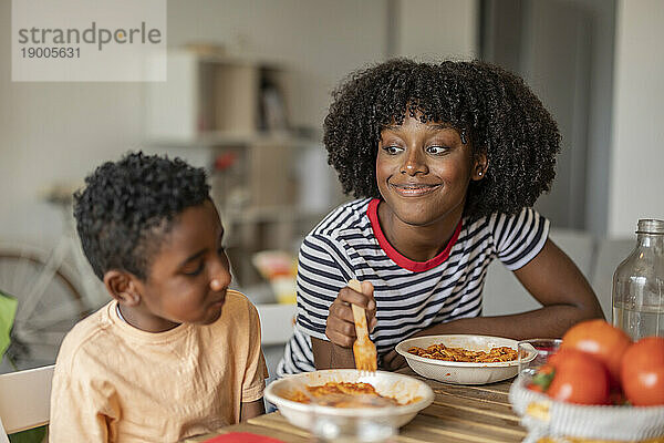 Lächelnde Frau mit Sohn beim gemeinsamen Essen zu Hause