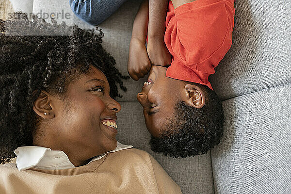 Happy mother and son lying on sofa at home