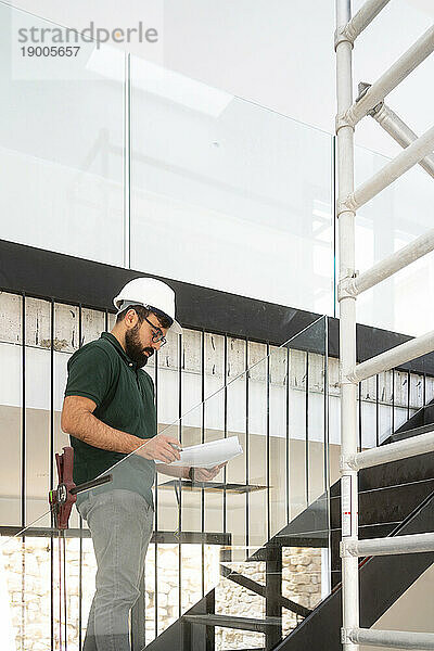 Architekt mit Dokument steht auf der Treppe auf der Baustelle