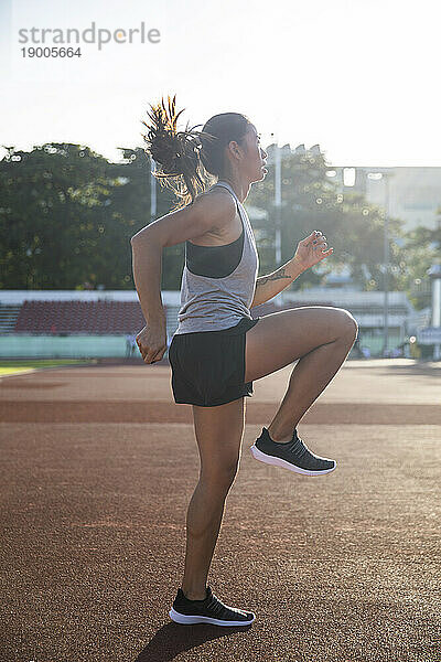 Athlete doing warm up exercise in sports field