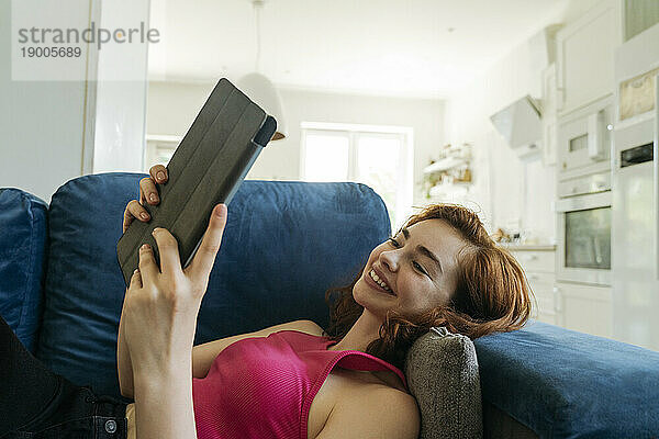 Glückliche junge Frau  die sich zu Hause entspannt und einen Tablet-PC benutzt