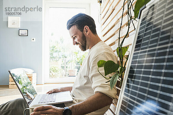 Glücklicher Geschäftsmann  der zu Hause am Laptop arbeitet