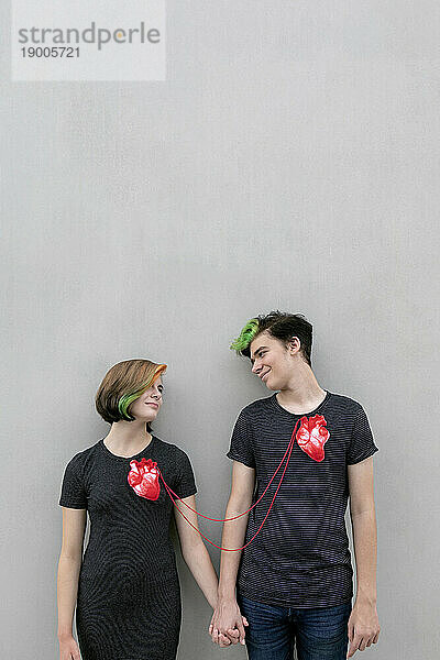 Teenage couple connected with hearts against gray background
