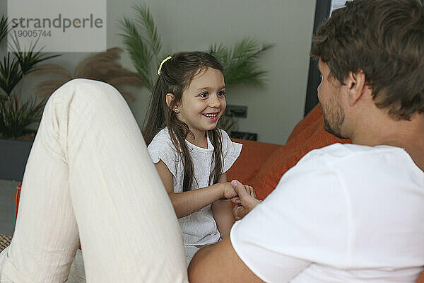 Smiling girl playing with father at home
