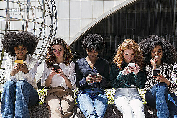 Geschäftsfrauen nutzen gemeinsam ihr Smartphone im Büropark