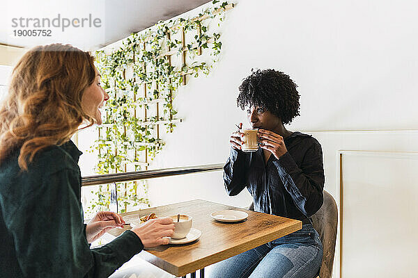 Glückliche Frau  die Kaffee trinkt und Zeit mit einer Freundin im Café verbringt
