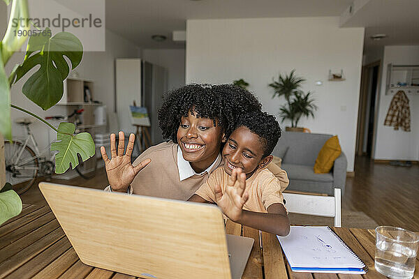 Glückliche Mutter und Sohn winken zu Hause per Videoanruf über den Laptop