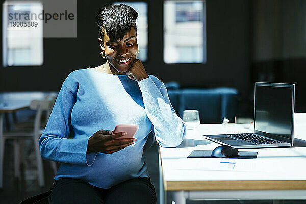 Smiling businesswoman using smart phone at desk