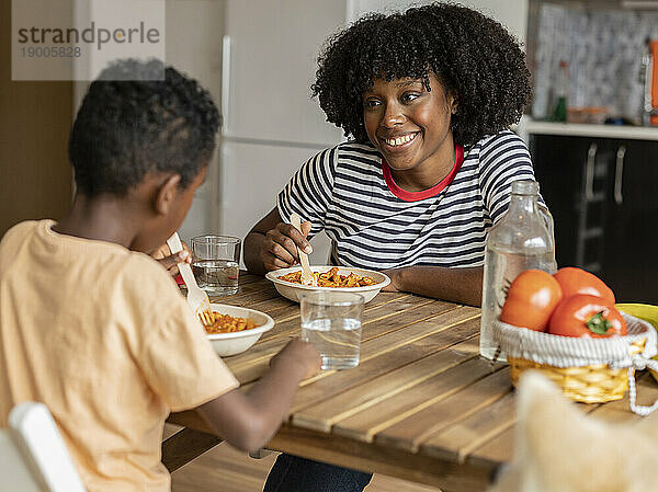 Lächelnde Mutter und Sohn beim gemeinsamen Essen zu Hause