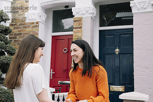 Lächelnde Freunde reden vor dem Haus