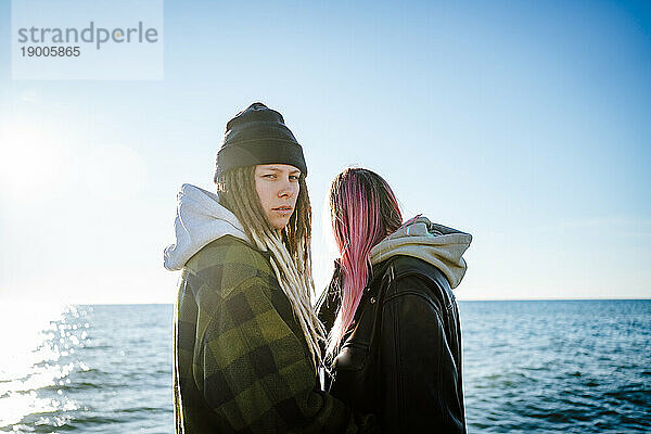 Zwei junge Frauen stehen zusammen am Meer