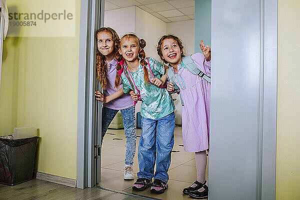 Smiling school children gesturing in classroom doorway
