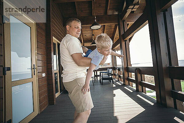 Father playing with son standing on porch
