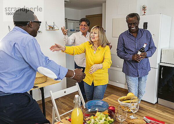Glückliche ältere multikulturelle Freunde  die zum Abendessen zu Hause ankommen