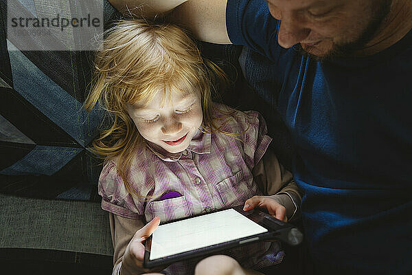 Tochter lernt am Tablet-PC und sitzt beim Vater