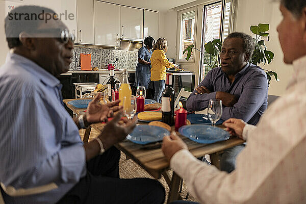 Multikulturelle ältere Freunde diskutieren am Esstisch zu Hause
