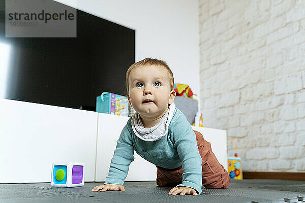 Cute baby boy crawling on floor at home