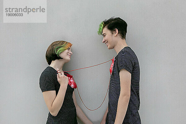 Teenager-Paar verband Herzen mit einem Seil vor grauem Hintergrund