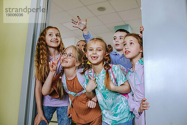 Cheerful school children gesturing in classroom door