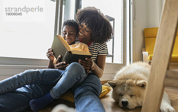 Glückliche Mutter und Sohn lesen zu Hause Buch