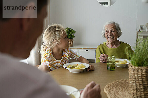 Lächelnde Familie beim Abendessen am Tisch zu Hause