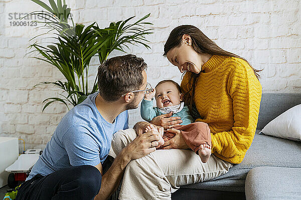 Happy parents playing with baby boy in living room at home