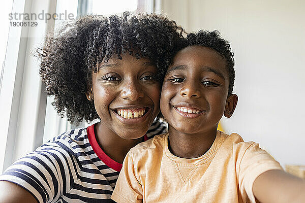 Lächelnde Mutter mit Sohn  die zu Hause ein Selfie macht