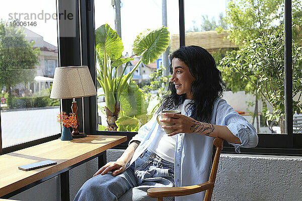 Lächelnde Frau genießt Kaffee im Café