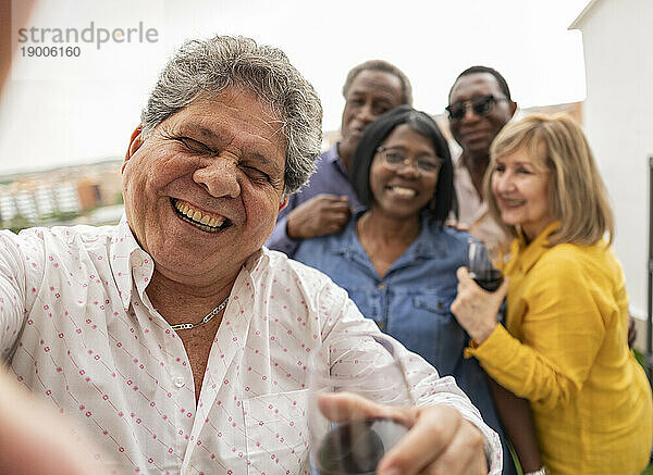 Glücklicher älterer Mann  der mit Freunden im Hintergrund genießt