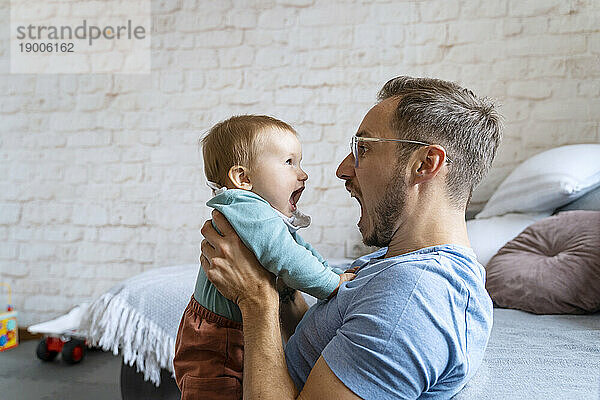 Verspielter Vater schreit mit kleinem Jungen zu Hause