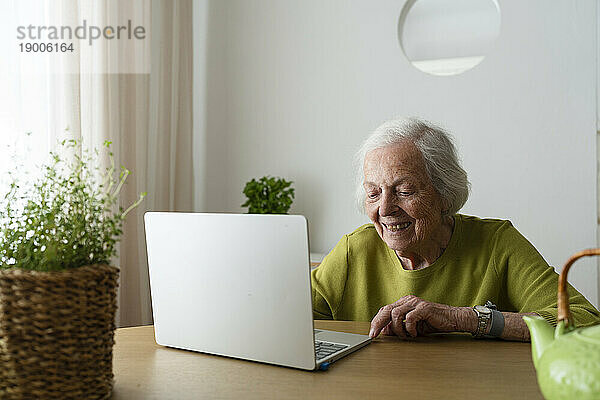 Ältere Frau benutzt Laptop auf Tisch zu Hause