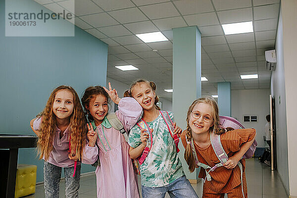 Smiling schoolgirls standing in school corridor