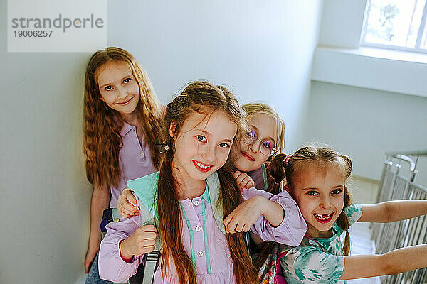 Smiling schoolgirls standing together on staircase