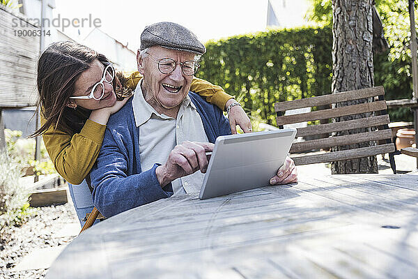 Mädchen mit Großvater benutzt Tablet-PC am Tisch