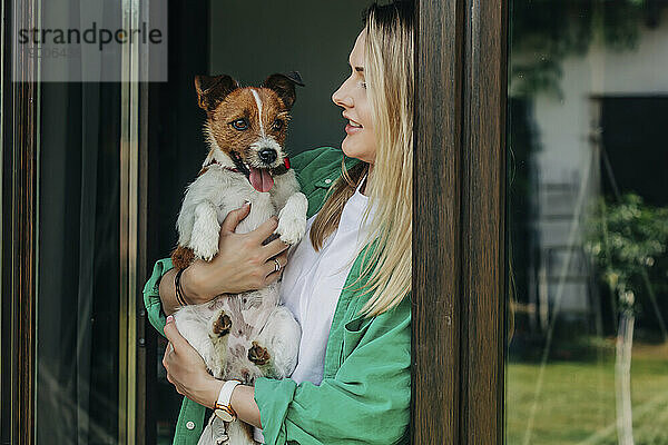 Frau hält Hund in der Nähe der Tür