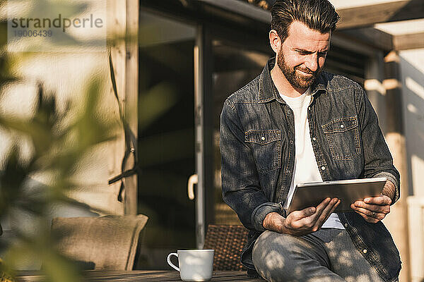 Lächelnder Mann  der an einem sonnigen Tag einen Tablet-PC benutzt