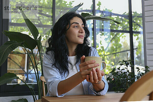 Nachdenkliche Frau hält Kaffeetasse im Café