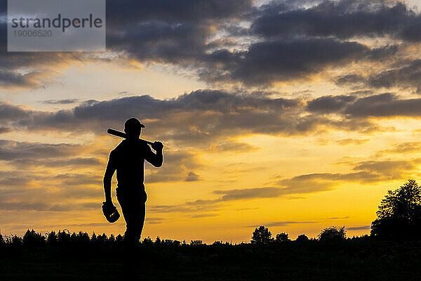 Silhouette eines Mannes mit Baseballschläger in der Abenddämmerung