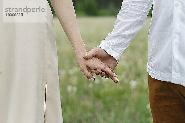 Couple holding hands on field