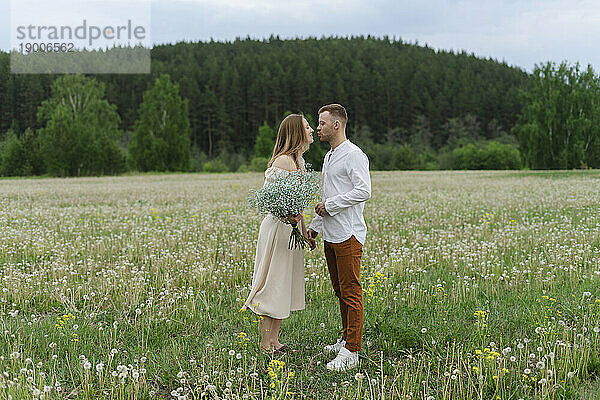 Junges Paar küsst sich auf einem Wildblumenfeld