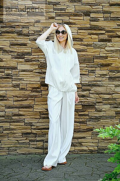 Urban Style Konzept  Frau in weißem Kapuzenpulli und lockerer Hose posiert im Freien
