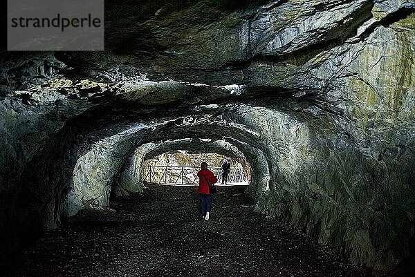 Eine Frau in einer roten Jacke geht tief in die Höhle mit Beleuchtung  Republik Karelien  Ruskeala Bergpark