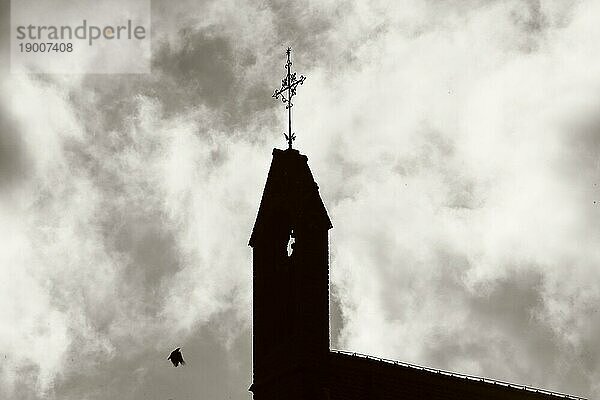 Silhouette eines Kirchturms mit fliegender Taube