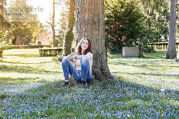 Junge Frau sitzt auf einer Frühlingsblumenwiese