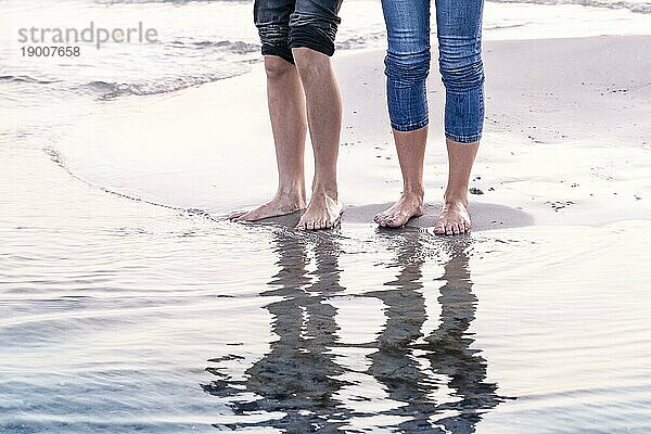 Die Beine von zwei Menschen  die sich im Meer spiegeln