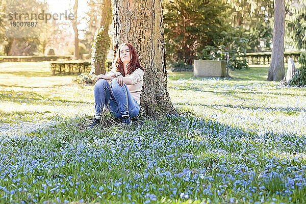 Junge lächelnde Frau auf einer Frühlingsblumenwiese sitzend