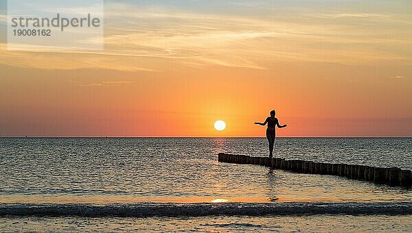 Frau balanciert bei Sonnenuntergang auf einer Leiste